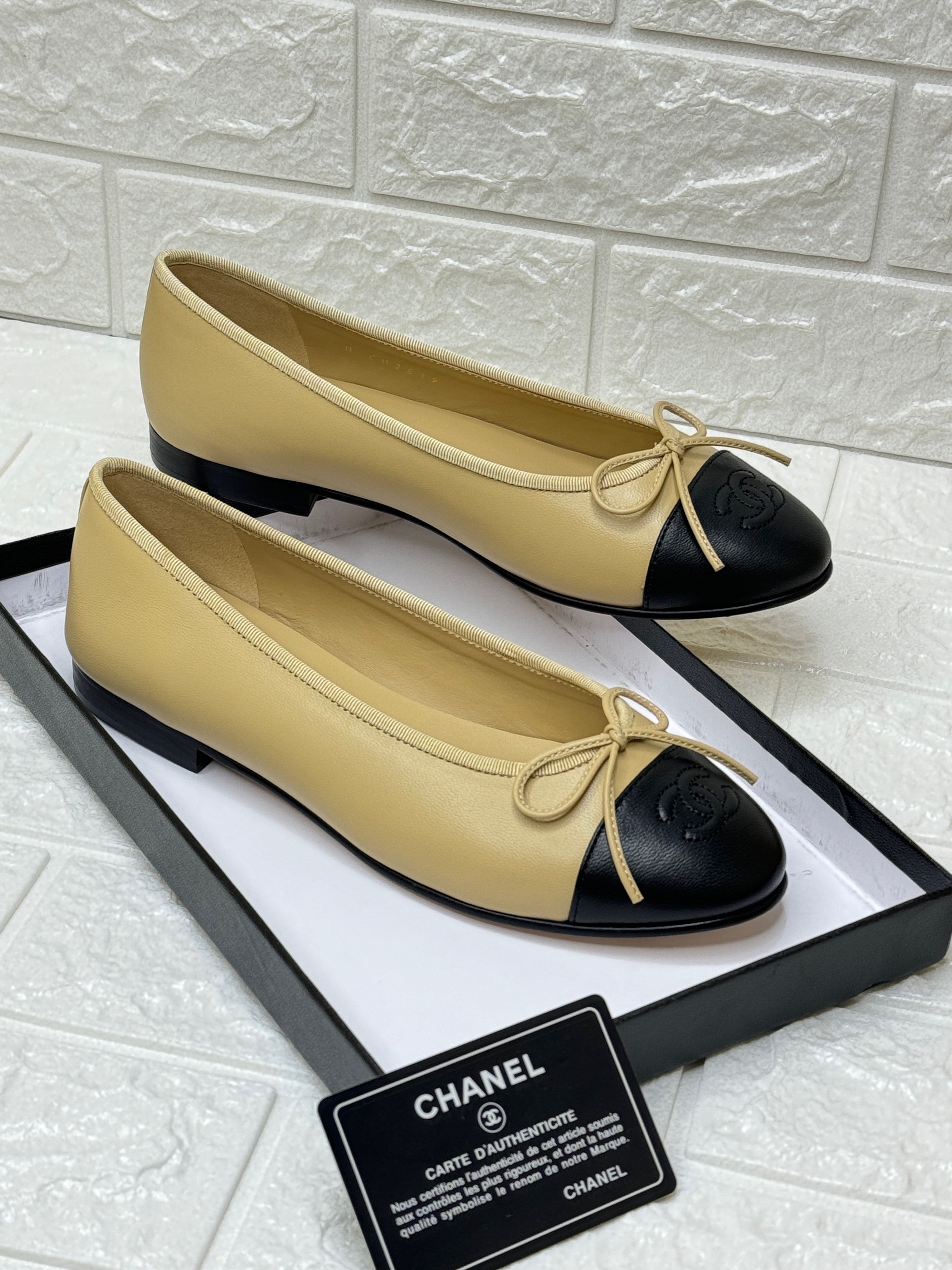 Chanel ballet flats in beige lambskin leather with a black cap toe and bow detail. image 1