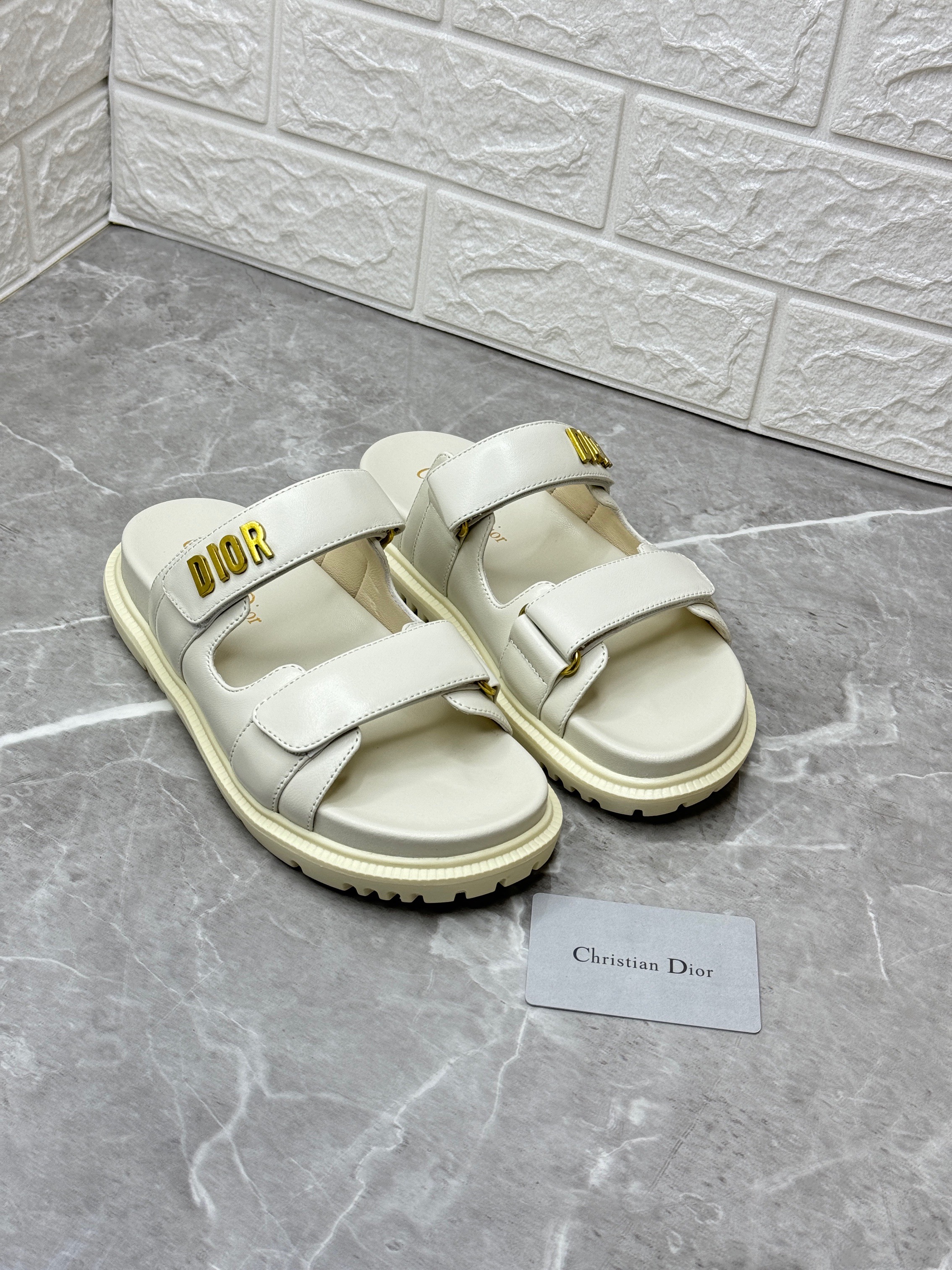 Dior Dioract slide sandals in white or cream lambskin leather with a gold-finish metal 'DIOR' signature. image 1