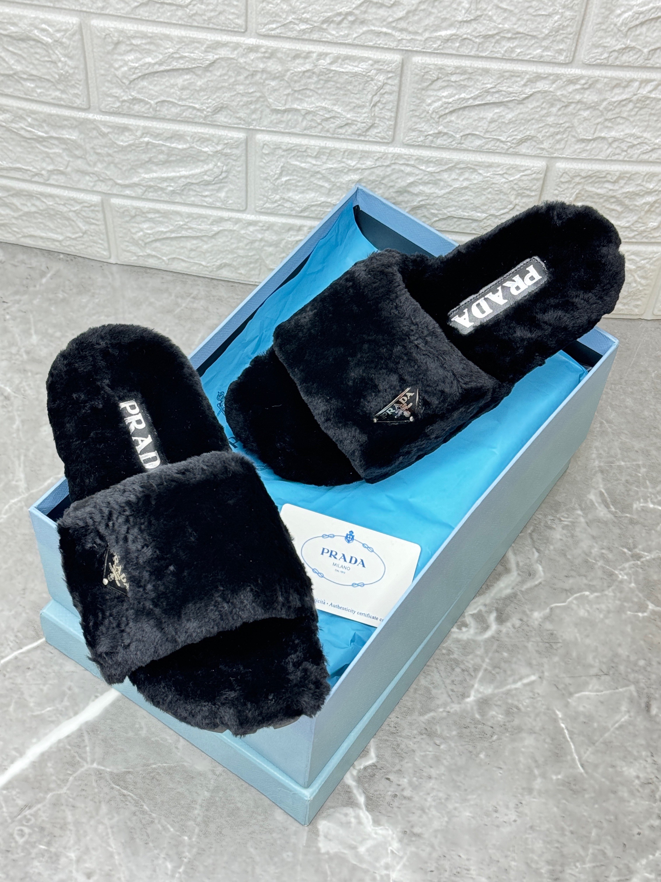 Prada shearling slides featuring the brand's iconic enameled triangle logo and a lug tread rubber sole. image 1